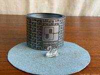Swan figurine placed in front of branded cylindrical presentation box on felt pad