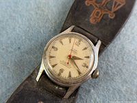 Close-up of watch dial showing Cox and Hamilton Jewellers text, red seconds hand, applied numerals