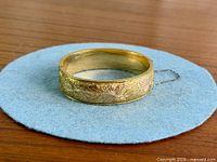 Full view of engraved Dunn Bros gold filled hinged bangle on felt pad