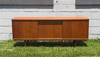Front view of Danish teak sideboard showing sliding doors and legs