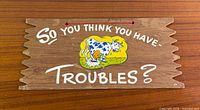 Front view of entire wooden sign showing text, cow graphic, and hanging cord