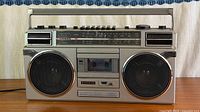 Front view of Sanyo M9927K boombox on table showing speakers, cassette deck, tuner scale, controls