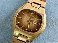 Dial close-up showing tiger eye finish, Seiko 5 logo, day-date window, wear on case