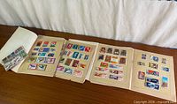 Overview of three open album pages and plastic sleeve of loose stamps