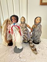 Four cloth dolls on lace table, focus on style and condition