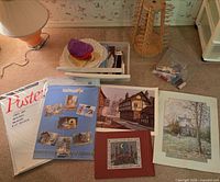 Lot overview showing posters, prints, spool rack, bin of doilies and bag of floss