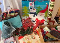 Overview of lot showing gift bags, wrapping paper roll, bows, ribbons, tags, tissue paper, shredded filler and decorative picks