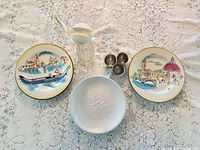 Top view showing all items: two Venetian plates, one white plate, three stainless cups, glass dressing bottle