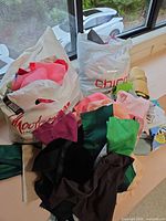 Two bags filled with colorful fabric scraps placed by window