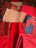 Assorted red, burgundy and peach fabric scraps including solids, stripes and patchwork prints
