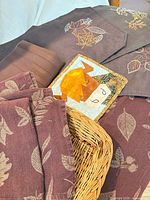 Burgundy table runner, napkins, placemats, quilted potholder and wicker basket showing leaf patterns and colours