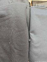Stack of black fabric yardage showing texture variations