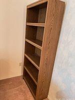 Right side angled view of entire bookcase showing five shelves and laminate finish