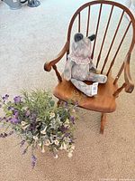 wooden rocking chair with teddy bear seated, floral arrangement on floor