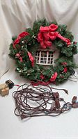 Front view of wreath showing greenery, bows, window diorama and wiring