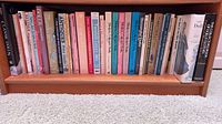 Full shelf showing approximately 30–40 doll and antique reference books