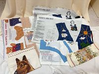 Overview of all fabric panels layered, visible Noah's Ark vest instructions, teddy puppet panel, bunny accessory panel, German Shepherd portrait, decorative strip