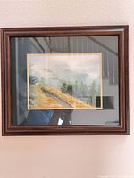 Front view of framed watercolor landscape in dark brown wood frame