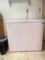 Front view of white Hisense chest freezer showing lid, brand logo, power cord and temperature dial