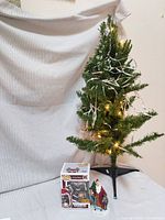 Lot overview showing pre-lit tree, Funko Krampus box, Saint Nicholas figurine