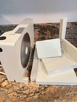 Overall slicer standing upright with blade exposed, carriage and tray components displayed