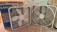 Two white 20-inch box fans side by side; original Lasko box visible