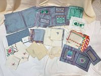 Overview of entire lot showing variety of napkins, coasters, embroidered panels and fabric samples
