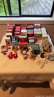 Table view showing multiple boxed Hallmark ornaments, loose figurines, plush teddies, angel, horse, crocheted items