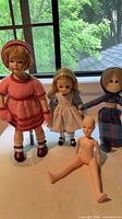 Front view of four dolls standing together showing outfits and condition
