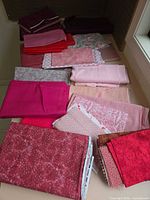 Overview of assorted pink and red cotton fabrics folded on surface