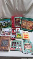 Assorted jigsaw puzzle boxes, brain teasers, booklet and bag displayed together