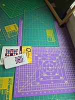 Group of green, teal and purple cutting mats with Quilter’s FabriCalc on top