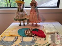 Two Heidi dolls on stands with crocheted potholders and extra clothing displayed