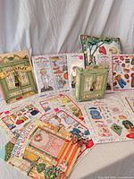 Front view of multiple Ann Estelle magnetic paper doll packs, green mini armoire, illustrated pillow, loose sticker sheets