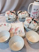 Complete set showing stacked cups, saucers, bowls, napkins and thermos