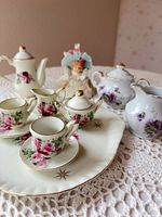 Front view of full tea set and doll showing patterns and gold trim