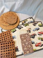 Overall view showing cork trivets, wood lattice trivet, quilted car-print placemats/pot holders, and folded kitchen linens