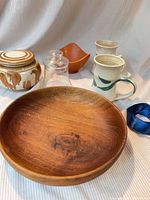 Overall lot showing wooden bowl, two mugs, ceramic jar, glass cloche, orange dish