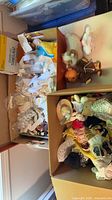 Two boxes showing mixed doll clothing, hats, plush and accessories
