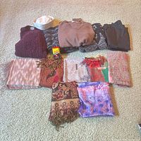 Group shot of sweaters, cap, ski pants, and eight scarves