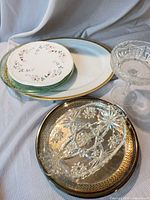 Group view showing stacked plates on Limoges platter, silver-plated tray foreground, glass compote right