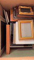 Box containing stacked wooden and plastic frames various finishes and sizes