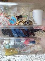Clear plastic drawer unit filled with assorted trims visible