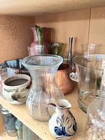Shelf showing all assorted vintage vases, ceramic pieces, copper pot and candlestick