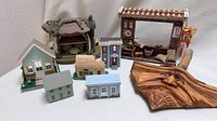 Group view of all miniature houses, market stall and carved face