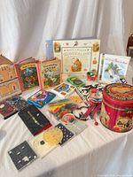Entire lot overview on tabletop showing books, games, checkers, tins and ornaments