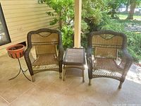 Two wicker armchairs, wicker side table, metal plant stand with pot on patio