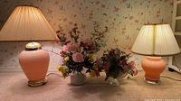 Both ceramic lamps with shades, two floral arrangements between