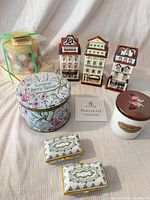 Group shot of all items: tin candle, jar candle, two trinket boxes, three townhouse figurines