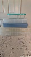 Stack of four plastic storage pieces showing relative sizes and lid colours